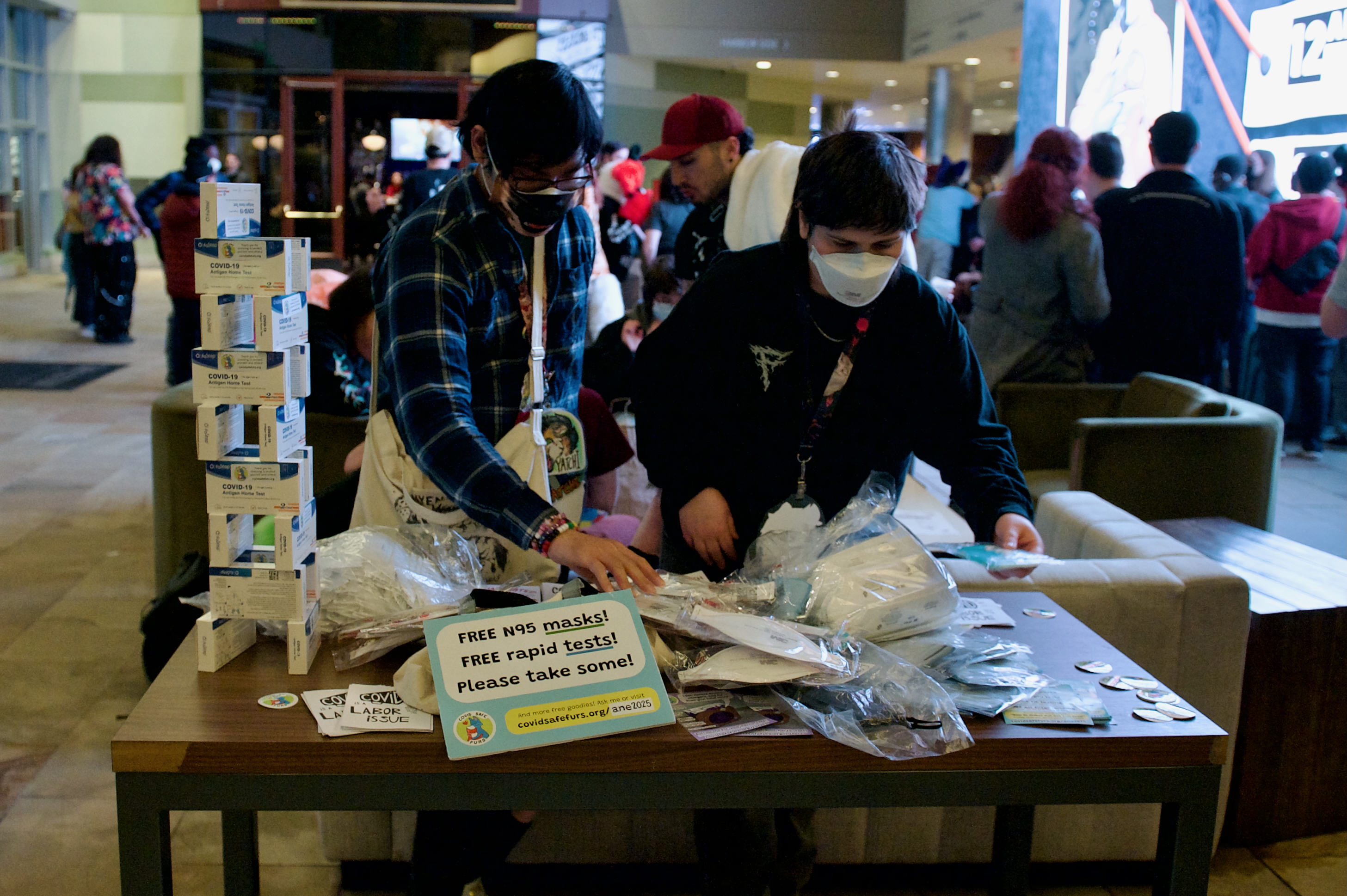 Two people arrange PPE on a table in the hotel lobby.